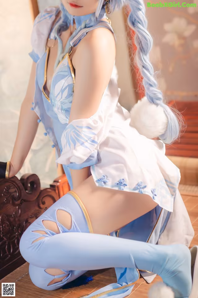 A woman in a blue and white outfit sitting on the floor.