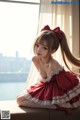 A woman in a red dress sitting on a window sill.