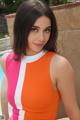 A woman in an orange and pink dress posing by a pool.