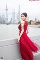 A woman in a red dress standing by the water.