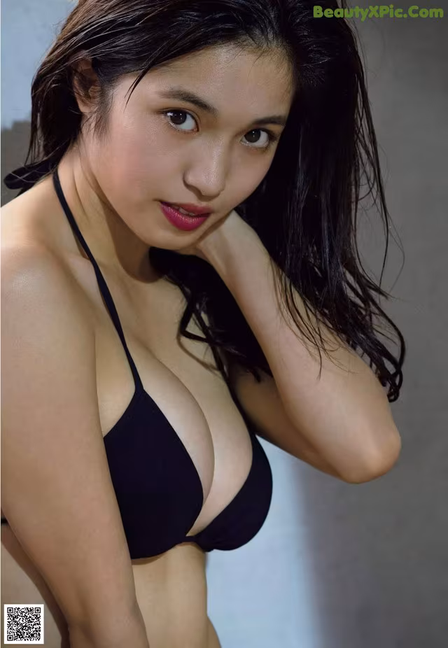 A woman in a black bikini posing for a picture.