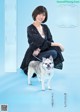 A woman sitting on a blue background with a dog.