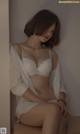 A woman in a white lingerie sitting on a wooden bench.