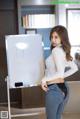 A woman standing in front of a white board with writing on it.