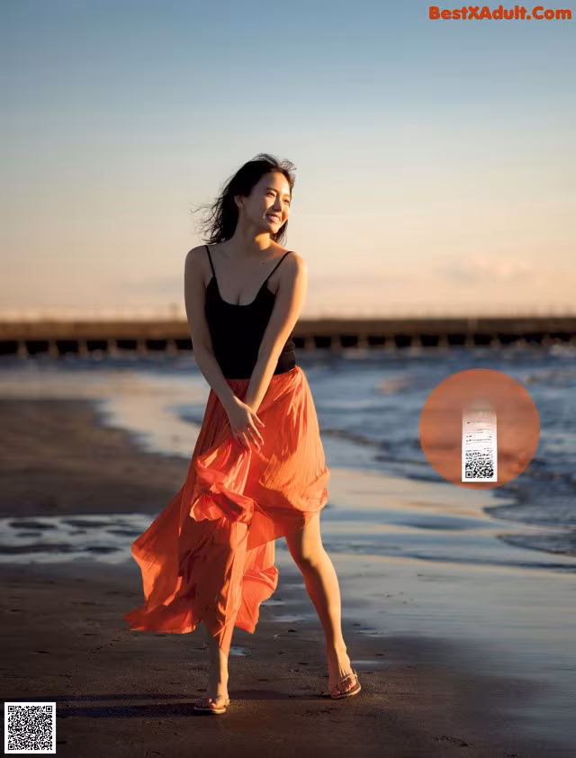 A woman walking on a beach near the ocean.