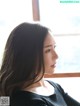 A woman with long brown hair looking out a window.