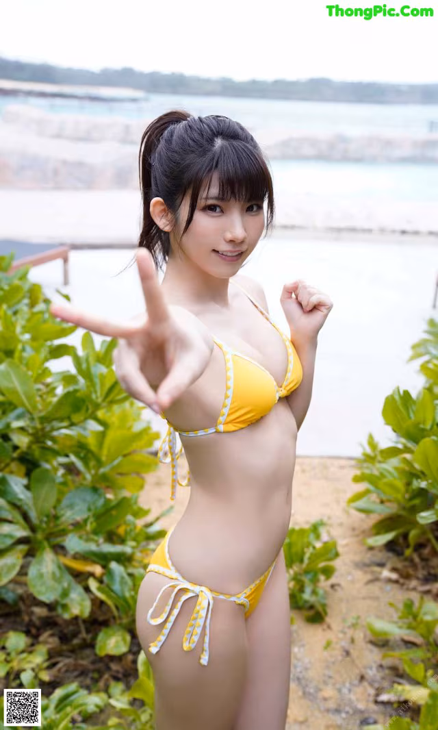 A woman in a yellow bikini posing for a picture.