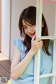 A woman leaning against a window with her hand on the window sill.