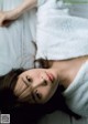 A woman laying on a bed with a white towel around her neck.