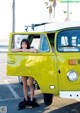 A woman leaning out the window of a yellow van.