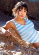 A woman in a blue and white striped bathing suit laying on rocks.