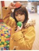 A woman in a yellow coat holding a green ball.