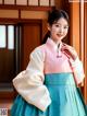 A woman in a blue and pink hanbok poses for a picture.