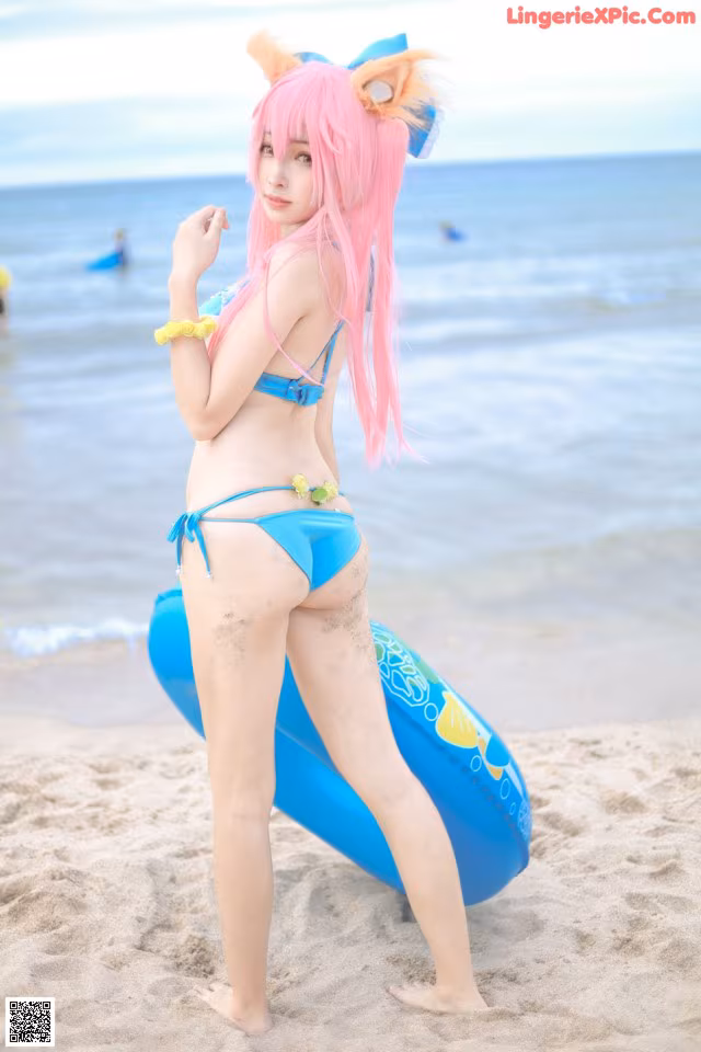 A woman in a bikini standing on a beach next to the ocean.