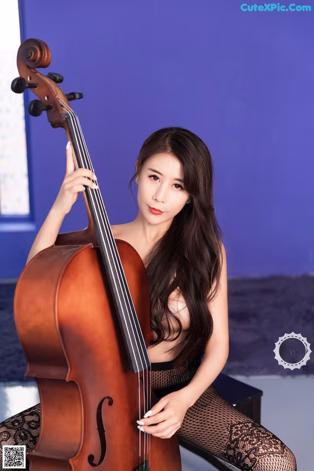 A woman sitting on a chair holding a cello.