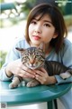 A woman holding a cat on top of a table.