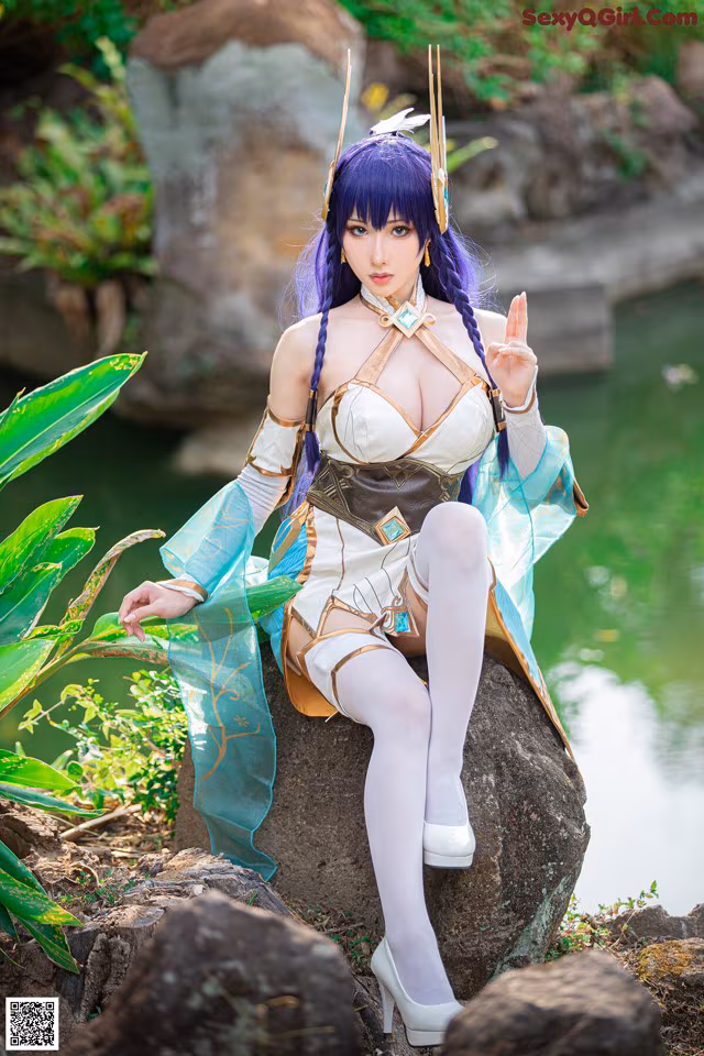 A woman sitting on top of a rock next to a pond.