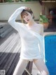 A woman in a white dress posing by a pool.