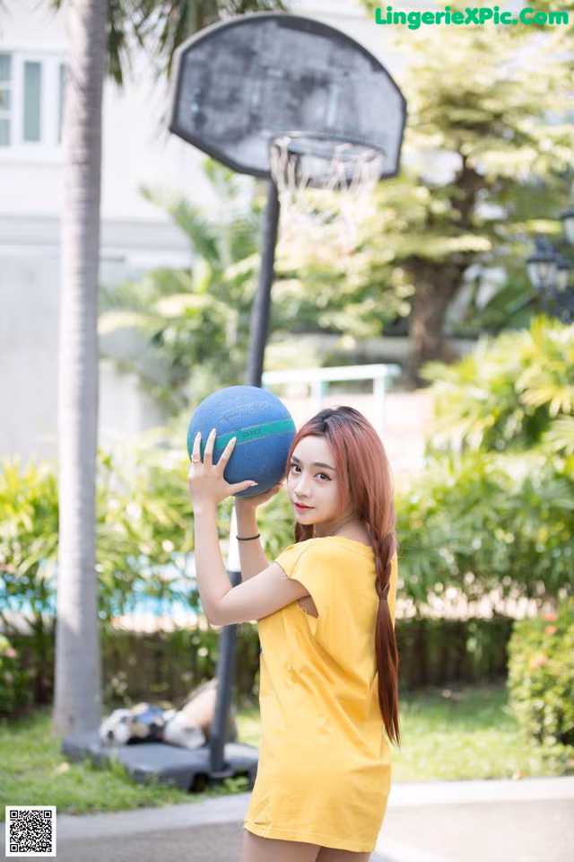 A woman holding a basketball in front of a basketball hoop.