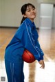 A young woman holding a basketball on a basketball court.