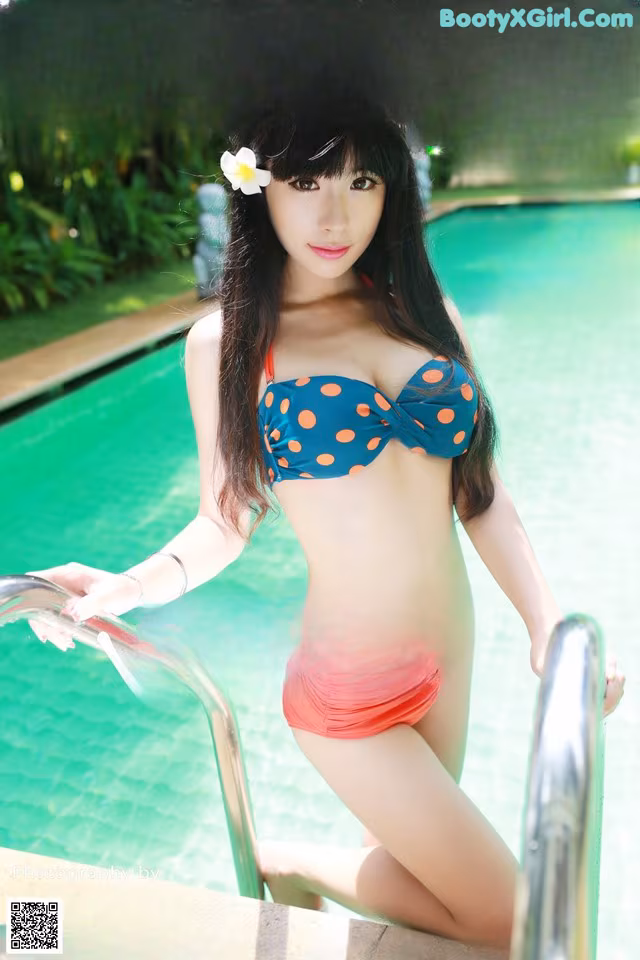 A woman in a bikini standing next to a swimming pool.