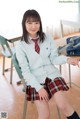 A young woman in a school uniform sitting on a chair.