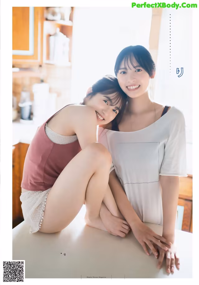 A couple of women sitting next to each other on a table.