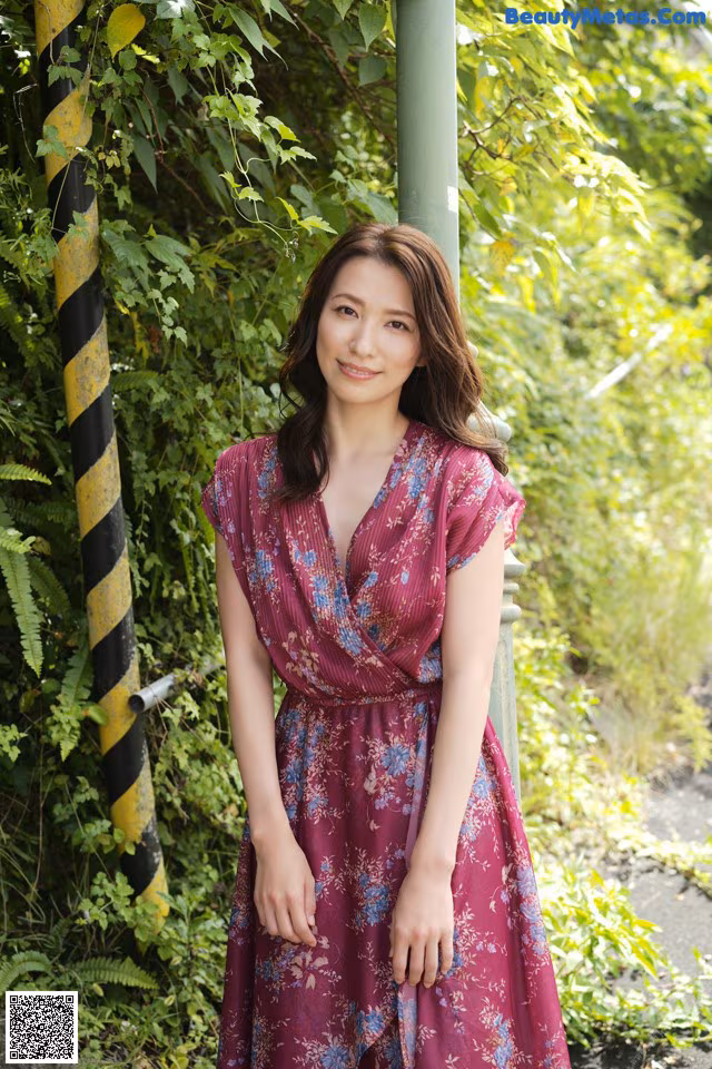 A woman in a purple dress leaning against a pole.