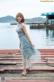 A woman standing on a dock next to a body of water.