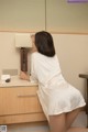 A woman in a white robe sitting on a desk.