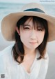 A woman wearing a straw hat on the beach.