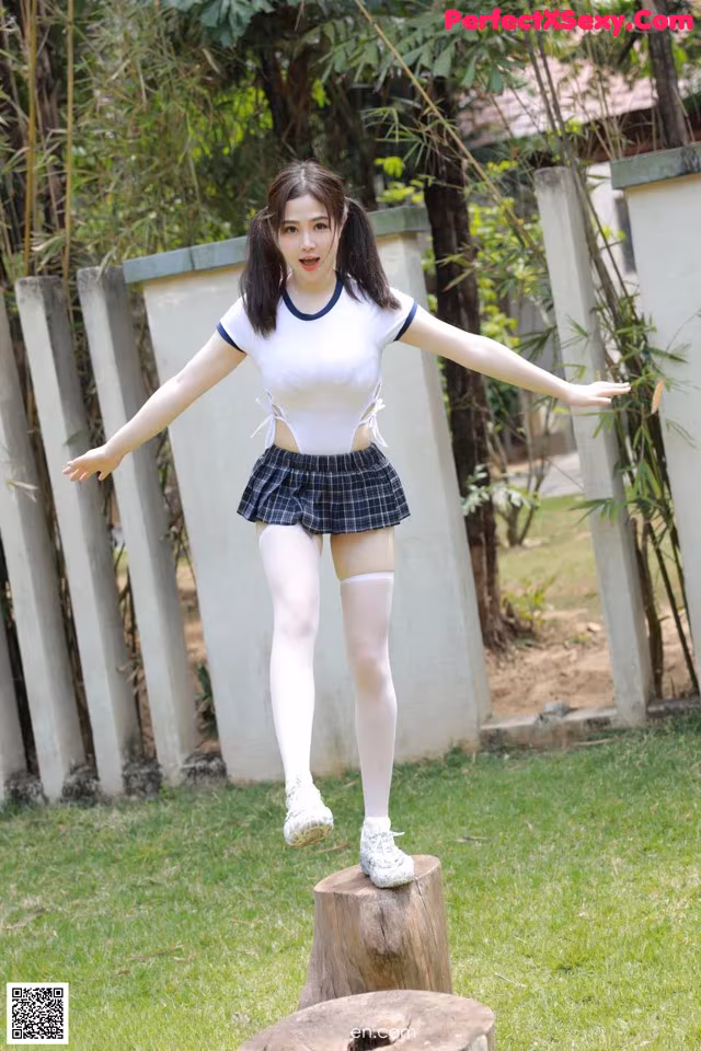 A woman in a school uniform is standing on a tree stump.