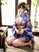 A woman in a blue kimono sitting on the floor.